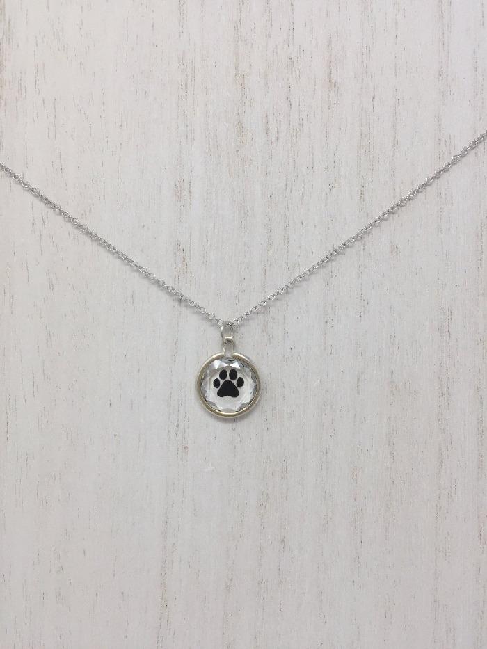 Picture of a sterling silver necklace with a circular pendant and a black paw inside of the pendant