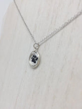 Load image into Gallery viewer, Close up picture of a sterling silver necklace with a circular pendant and a black paw inside of the pendant
