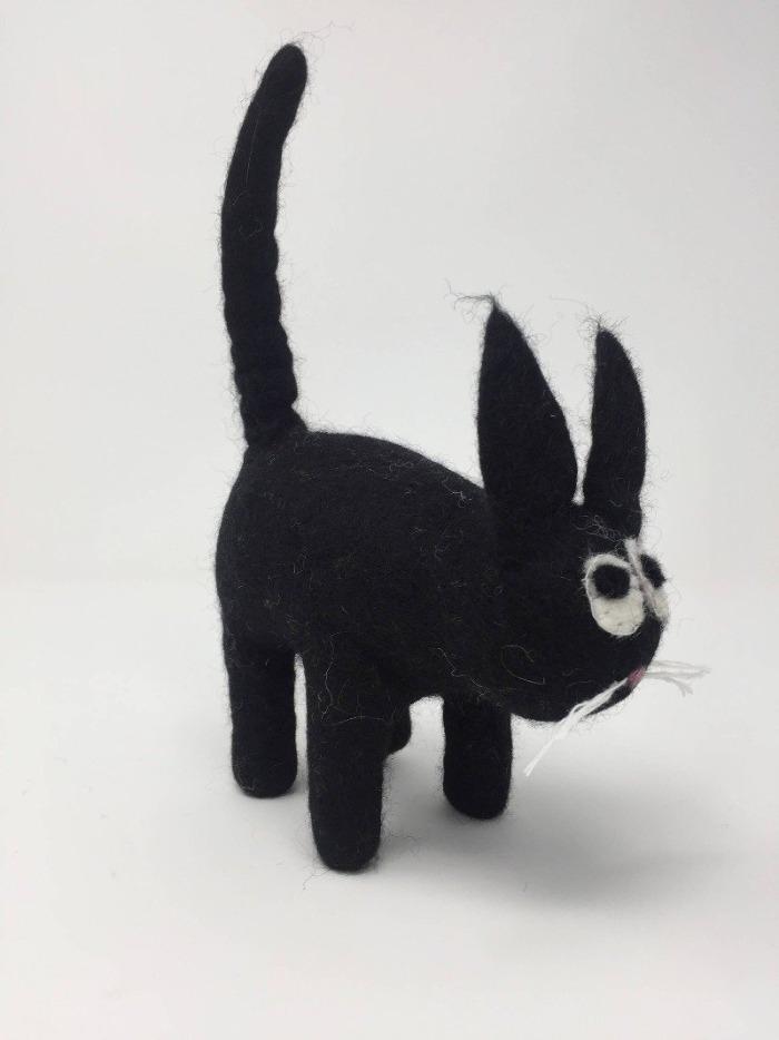 Picture of a black felt cat standing on a white surface