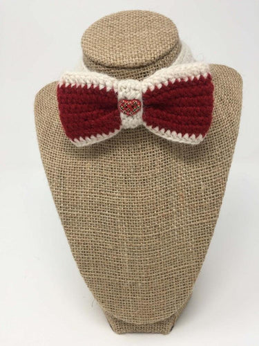 Red and white hand-knitted bow tie pet collar around a tan brown bust 