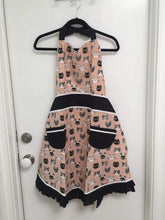 Load image into Gallery viewer, Pink and black colored kitchen apron hanging from a black hanger, hanging from a white door 
