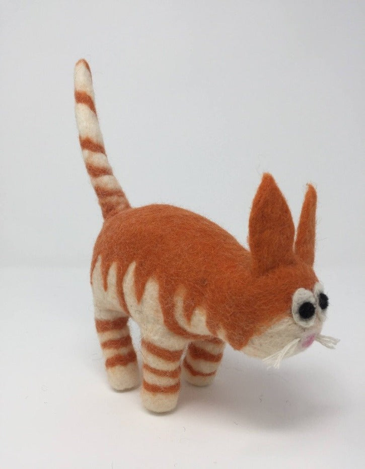 Picture of a striped orange felt cat standing on an all white surface 