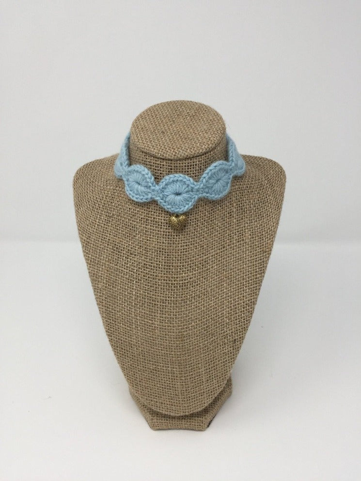 Picture of a light blue pet collar with a gold colored pendant around a tan brown bust 