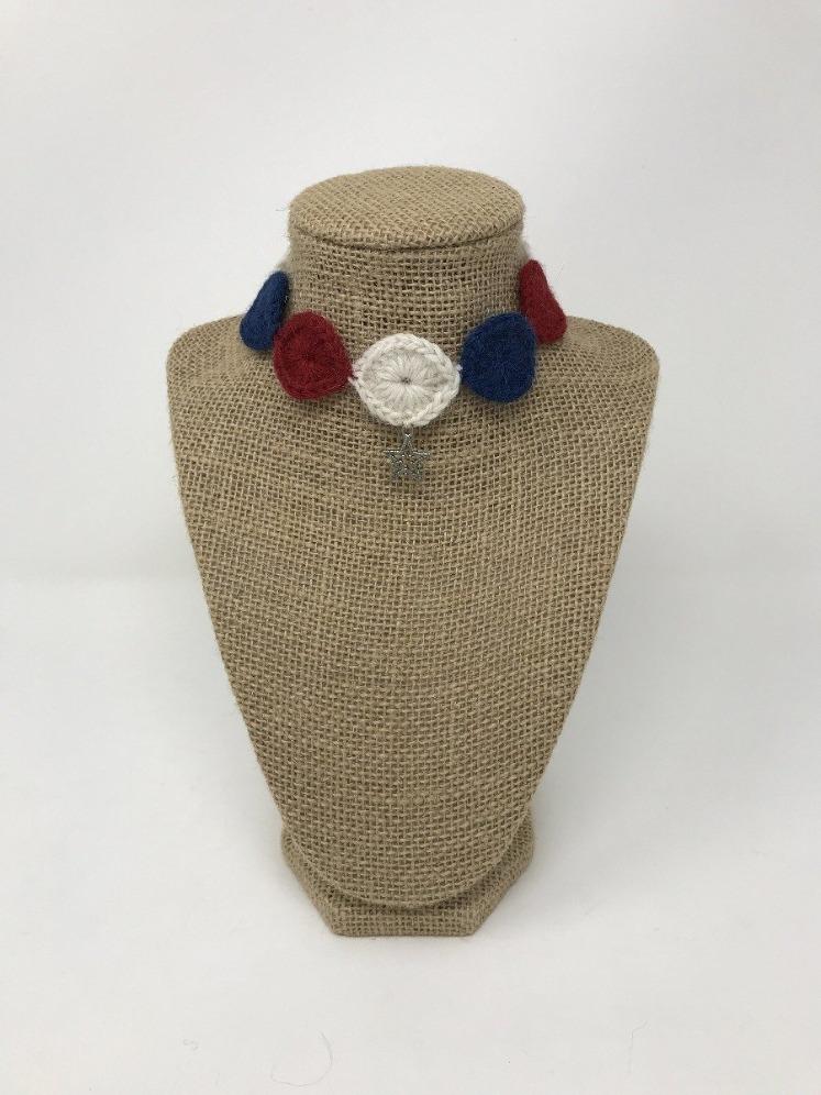 Red, white, and blue hand-knitted pet collar with silver star of David charm around a tan brown bust 