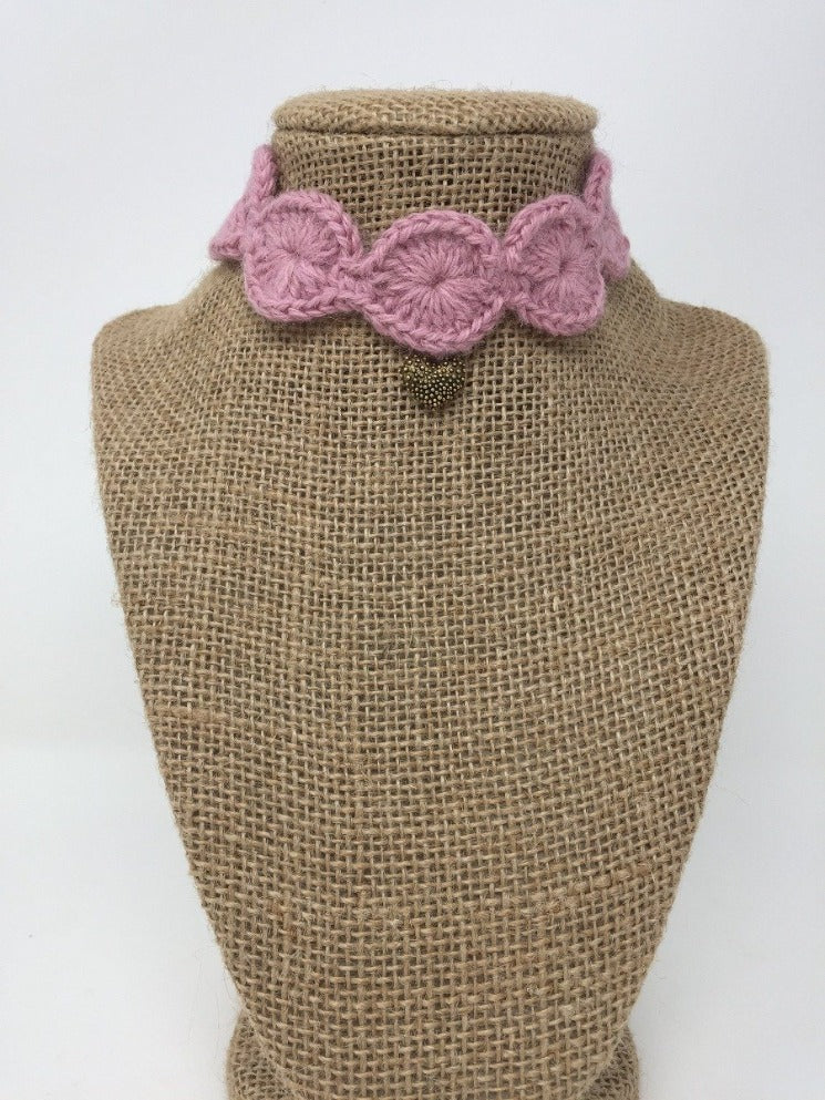 Picture of a Mauve pink hand-knitted Alpaca pet collar with gold colored pendant around a tan brown bust