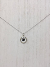 Load image into Gallery viewer, Picture of a sterling silver necklace with a circular pendant and a black paw inside of the pendant
