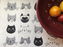 Load image into Gallery viewer, White cat-themed dish rack mat, featuring white, black, and grey cats. on a white kitchen surface. there are some vegetables in a red bowl laying on the towel
