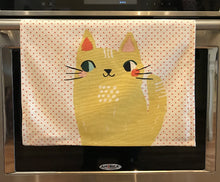 Load image into Gallery viewer, White kitchen towel with red dots and two big yellow cats on it hanging from an oven handle bar
