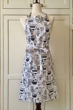 Load image into Gallery viewer, Picture of a white and black kitchen apron on a mannequin featuring black cats 
